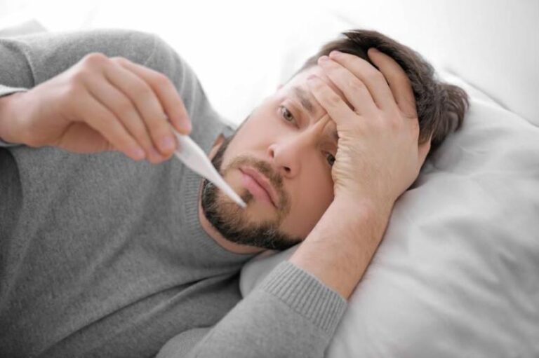 Young,Ill,Man,Measuring,Temperature,While,Lying,In,Bed,At