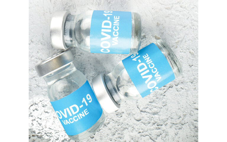 Above view of ampules with covid- vaccine on gray sand backgroun