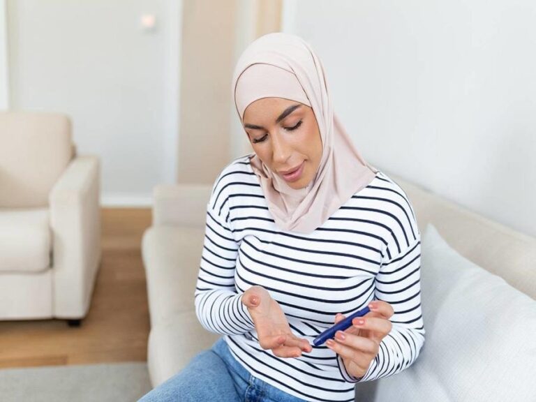 Arabic muslim woman doing blood sugar test at home in a living room.