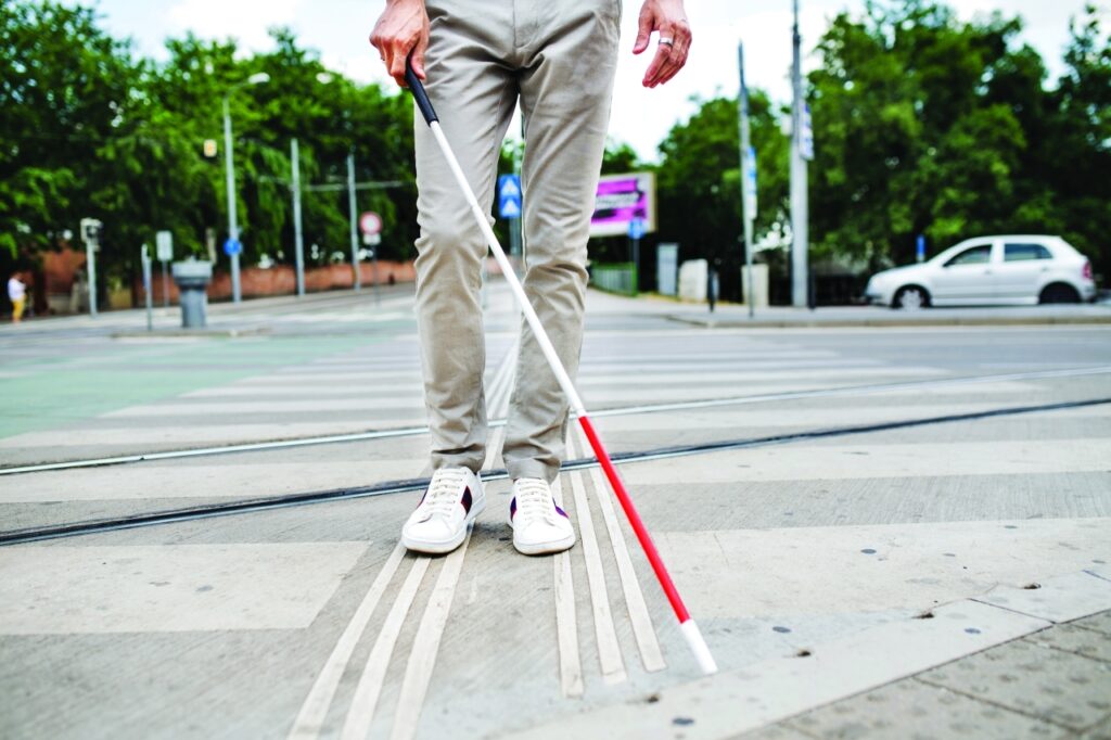 Midsection,Of,Young,Blind,Man,With,White,Cane,Walking,Across