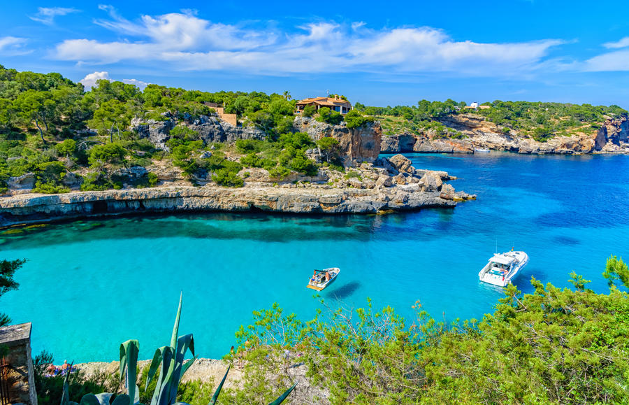 Summer holiday scene with boats on turquoise sea water of Mallor