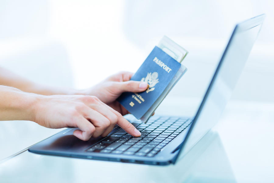 Closeup,Male,Person's,Hands,Holding,A,Passport,While,Typing,On