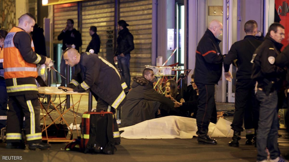 General view of the scene that shows rescue services personnel working near the covered bodies outside a restaurant following a shooting incident in Paris